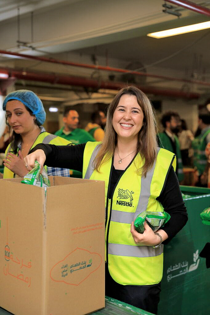 A smiling Nestlé colleague packing food donations